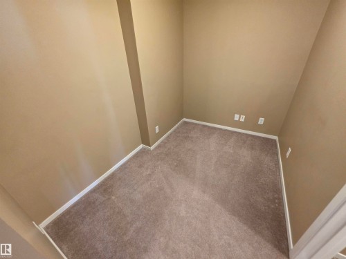 Neutral-toned carpeting and walls with white baseboards create a versatile interior space - 319 5816 Mullen Place, Edmonton, AB 