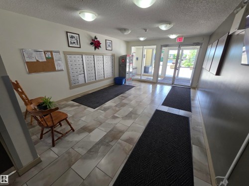 Building entrance featuring wood-finish tile flooring, recessed lighting, and glass entry doors - 319 5816 Mullen Place, Edmonton, AB 
