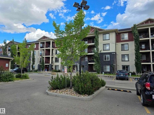 Multi-story building featuring light-colored siding, dark red siding, and dark stone accents - 319 5816 Mullen Place, Edmonton, AB 