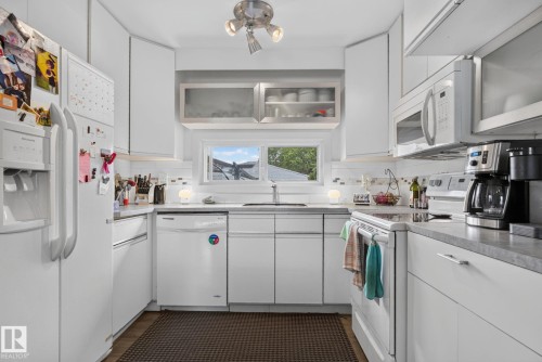Bright kitchen featuring white cabinetry, light countertops, and a white subway tile backsplash - 7539 149A Avenue, Edmonton, AB 