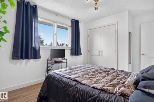 Bedroom featuring white walls, wood-finish flooring, and a double-pane window - 7539 149A Avenue, Edmonton, AB 