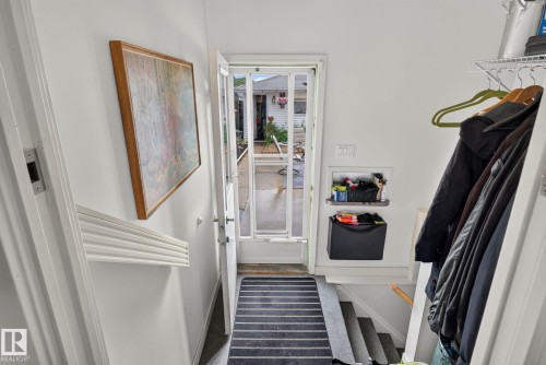 Entryway featuring a white storm door, striped floor mat, and built-in shelving - 7539 149A Avenue, Edmonton, AB 