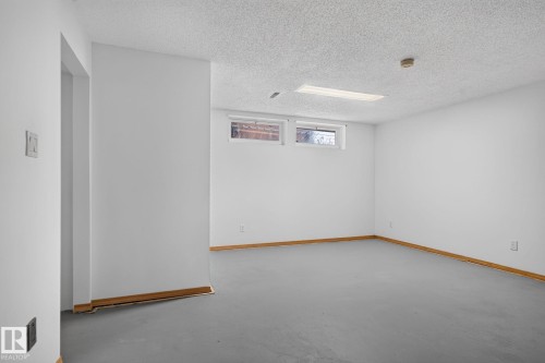 Spacious room featuring light gray flooring, white walls, and wood-finish baseboards - 7539 149A Avenue, Edmonton, AB 