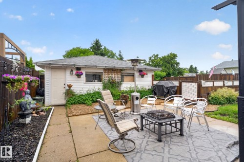Paved patio area featuring an outdoor rug, surrounded by a wood fence with lattice accents - 7539 149A Avenue, Edmonton, AB 