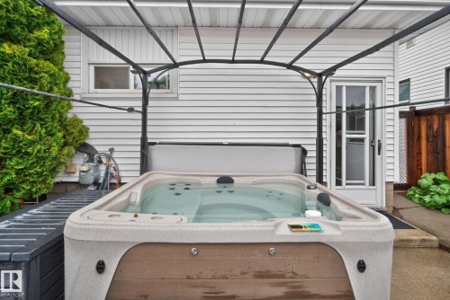 Outdoor hot tub with a protective cover, set under a metal pergola - 7539 149A Avenue Nw, Edmonton, AB - Outdoor With Exterior