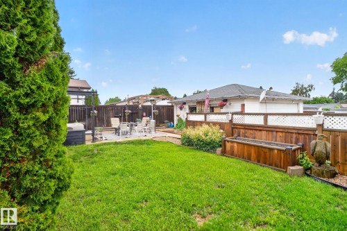 Manicured lawn with a paver patio area, bordered by a wood fence featuring white lattice accents - 7539 149A Avenue, Edmonton, AB 