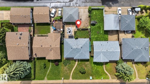 Aerial perspective showcasing a residential property with a light grey shingle roof, a paved driveway, and a backyard featuring a patio area - 7539 149A Avenue, Edmonton, AB 