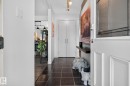 Entryway featuring dark square tile flooring, white walls, and a white paneled front door with decorative glass - 7539 149A Avenue, Edmonton, AB 