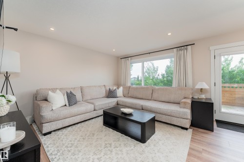 Spacious living area featuring light wood-finish flooring, recessed ceiling lighting, and a large window providing ample natural light - 584 Meadowview Drive, Fort Saskatchewan, AB 