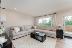 Spacious living area featuring light wood-finish flooring, recessed ceiling lighting, and a large window providing ample natural light - 