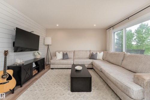 Living area featuring wood-finish flooring, a shiplap accent wall, recessed lighting, and large sliding glass doors - 584 Meadowview Drive, Fort Saskatchewan, AB 