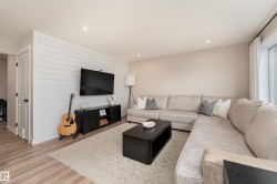 Living area featuring a shiplap accent wall, light wood-finish flooring, recessed lighting, and a large window with curtain rods - 