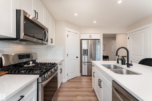 Modern kitchen featuring white cabinetry, stainless steel appliances, a subway tile backsplash, light wood-finish flooring, and recessed lighting - 584 Meadowview Drive, Fort Saskatchewan, AB 