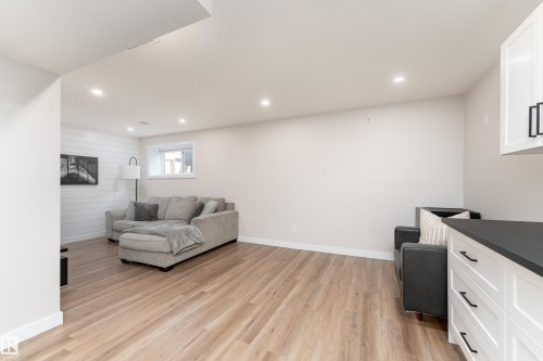 Spacious room featuring light wood-finish flooring, recessed lighting, and a white shiplap accent wall - 584 Meadowview Drive, Fort Saskatchewan, AB 