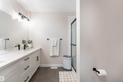 Bathroom featuring a double vanity with white cabinetry, matte black hardware, and a white countertop - 