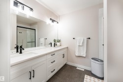 Double vanity featuring white cabinetry, integrated sinks, black hardware, and an expansive mirror - 