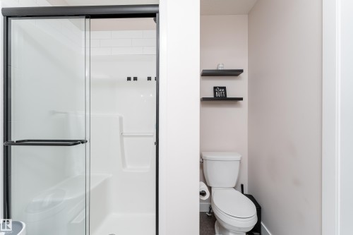 Walk-in shower with black-framed glass sliding door and integrated seating - 584 Meadowview Drive, Fort Saskatchewan, AB 