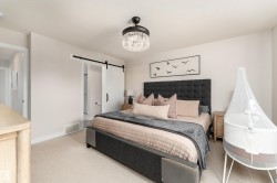 Carpeted bedroom featuring a barn door entry, a built-in ceiling light fixture, and a light-toned wall finish - 
