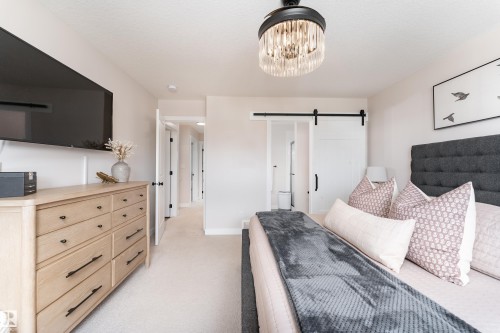 Bedroom featuring light-toned walls, plush carpet flooring, and a decorative ceiling light fixture - 584 Meadowview Drive, Fort Saskatchewan, AB 