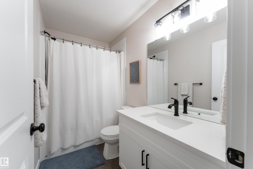 Bathroom featuring a white vanity with integrated sink, a dark bronze faucet, and a large wall-mounted mirror - 584 Meadowview Drive, Fort Saskatchewan, AB 
