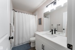 Bathroom featuring a white vanity with integrated sink, a dark bronze faucet, and a large wall-mounted mirror - 