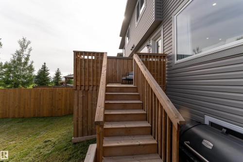 Rear exterior featuring a wooden deck with railing, stairs, and privacy screen - 584 Meadowview Drive, Fort Saskatchewan, AB 