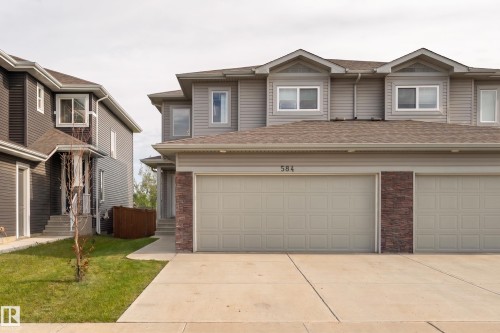Two-story property featuring light grey siding, a brown shingle roof, and dormer windows - 584 Meadowview Drive, Fort Saskatchewan, AB 