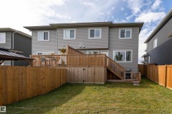 Rear elevation featuring gray horizontal siding, a multi-level wood deck, and a grass lawn - 