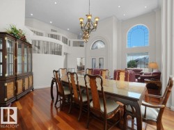 Grand entry foyer featuring soaring ceilings, a sweeping staircase with custom railing, and gleaming wood-finish flooring - 