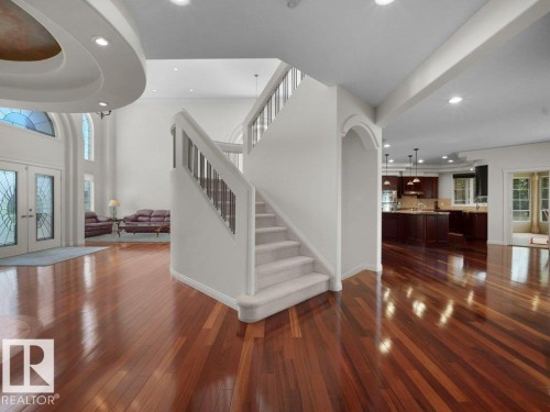Grand entryway featuring a double staircase with metal balusters, hardwood flooring, and a two-story foyer with decorative arched windows - 2423 Tegler Green, Edmonton, AB 