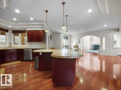 Kitchen featuring rich wood cabinetry, stainless steel dishwasher, granite countertops, and wood-finish flooring - 