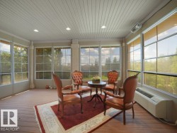 Sunroom featuring extensive window-paned walls, wood-finish flooring, and a beadboard ceiling with recessed lighting - 