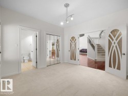 Neutral tone carpeted room with track lighting, featuring decorative paneled double doors and a mirrored closet - 