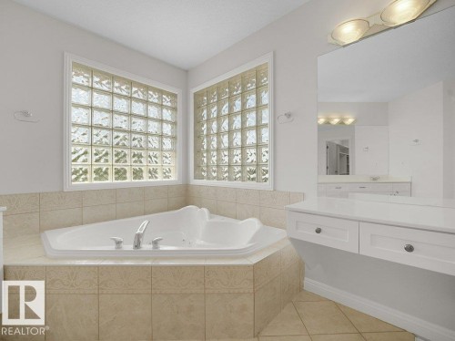 Corner soaking tub surrounded by beige tile - 2423 Tegler Green, Edmonton, AB 