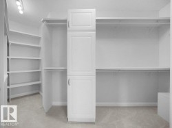 Spacious walk-in closet featuring built-in white cabinetry, extensive shelving, hanging rods, and recessed ceiling lighting - 