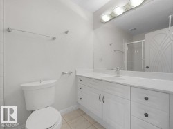 Bathroom featuring a white vanity with integrated sink, a large wall-mounted mirror, and tile flooring - 