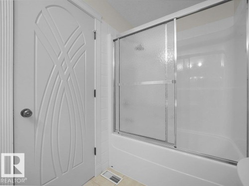 White fiberglass tub and shower enclosure with sliding frosted glass doors - 2423 Tegler Green, Edmonton, AB 