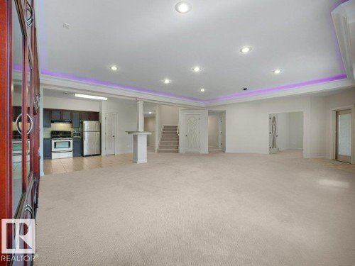Spacious room featuring neutral carpeting, recessed lighting, and a tray ceiling with accent lighting - 2423 Tegler Green, Edmonton, AB 