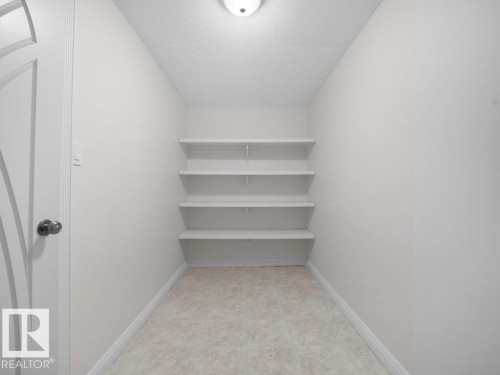 Recessed storage area featuring four built-in shelves, light neutral wall paint, and ceramic tile flooring - 2423 Tegler Green, Edmonton, AB 