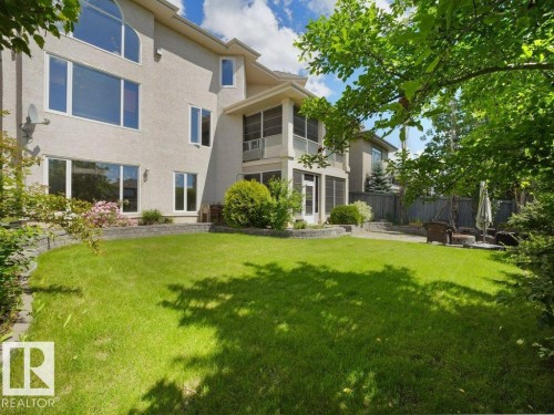 Stucco exterior featuring an arched window, multiple large windows, and a screened-in porch - 2423 Tegler Green, Edmonton, AB 