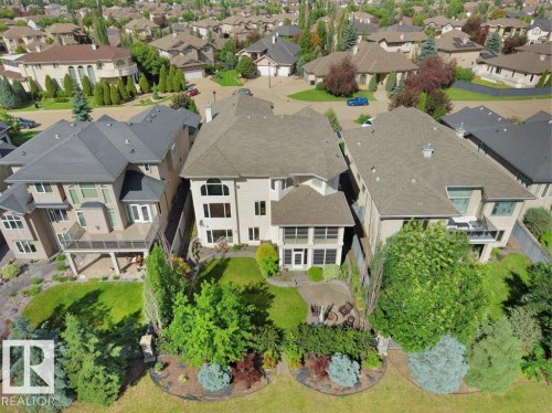 Stone exterior featuring a tiered backyard, a ground-level patio, a covered deck, and mature landscaping - 2423 Tegler Green, Edmonton, AB 