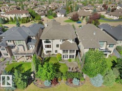 Stone exterior featuring a tiered backyard, a ground-level patio, a covered deck, and mature landscaping - 