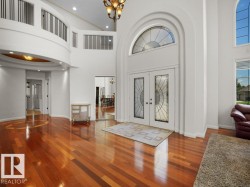 Grand entryway featuring double doors with decorative glass panels, a prominent arched transom window, and high ceilings - 