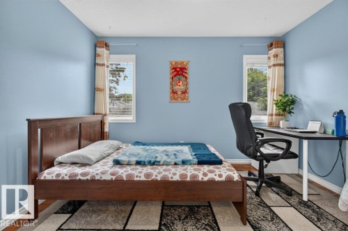 Bright room with light blue painted walls, wood-finish flooring, white baseboards, and two windows providing natural light - 11330 101 Street, Edmonton, AB 