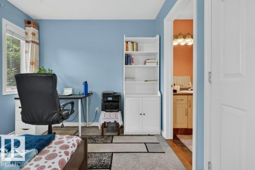 Room with light blue wall paint, a white-framed window, and a built-in white shelving unit with lower cabinet storage - 11330 101 Street, Edmonton, AB 