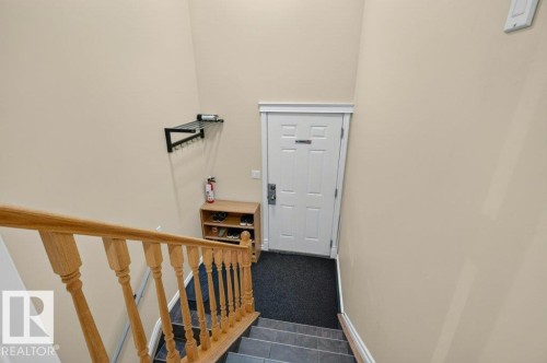 Staircase with light wood banister and balusters leading to a paneled entry door - 11330 101 Street, Edmonton, AB 