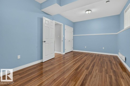 Interior room featuring wood-finish flooring, two white panel doors, and light blue walls with white chair rail molding - 11330 101 Street, Edmonton, AB 