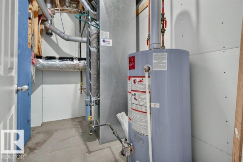 Mechanical room featuring a water heater, furnace, and exposed ductwork - 11330 101 Street, Edmonton, AB 