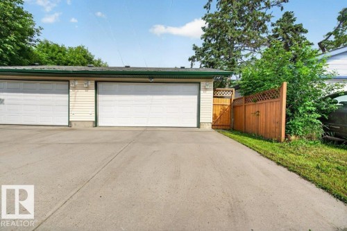Two-car garage featuring white paneled doors, cream siding, and a dark green trim - 11330 101 Street, Edmonton, AB 