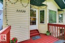 Inviting front entry featuring light-colored siding, a red-painted deck, and a glass-paneled storm door - 11330 101 Street, Edmonton, AB 